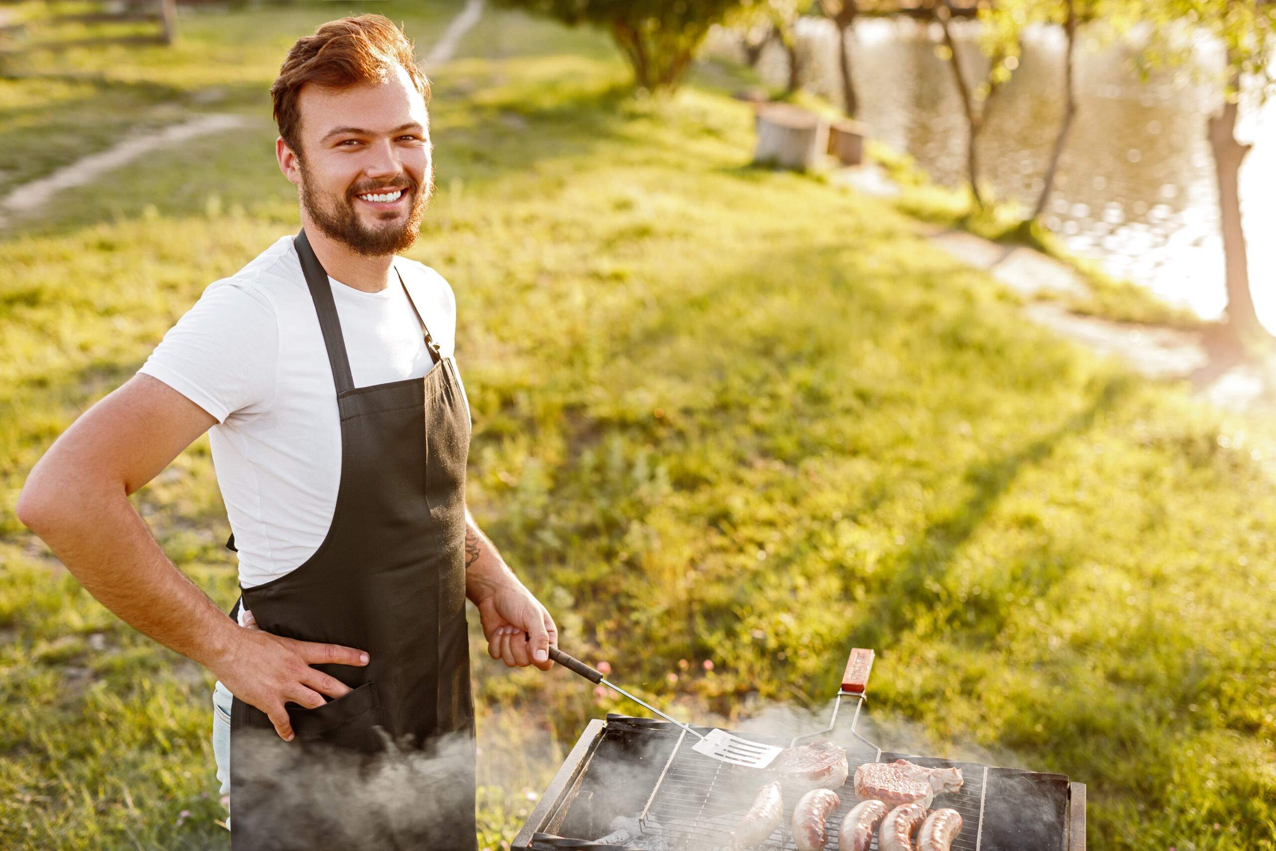 Positive man cooking meat on grill